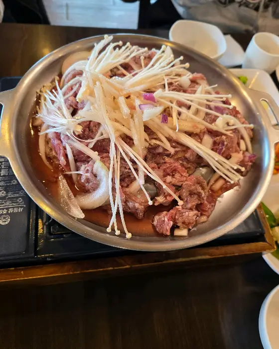 불고기 전골 냄비에 양파, 버섯, 파가 듬뿍 담겨 있는 모습