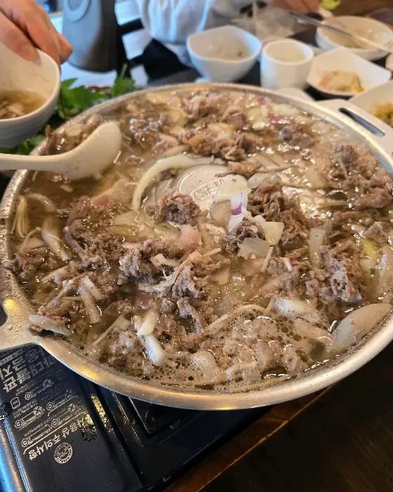 끓고 있는 불고기 전골 냄비의 모습, 국물과 고기가 조화롭게 섞여 있다.