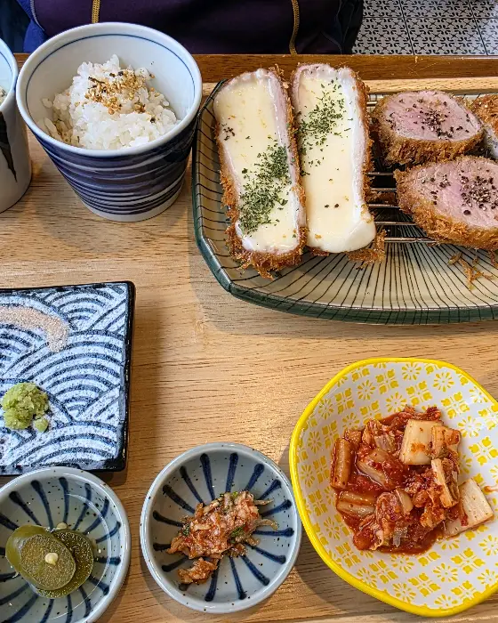 치즈가 흘러내리는 돈까스와 곁들임 찬, 밥이 함께 나온 모습