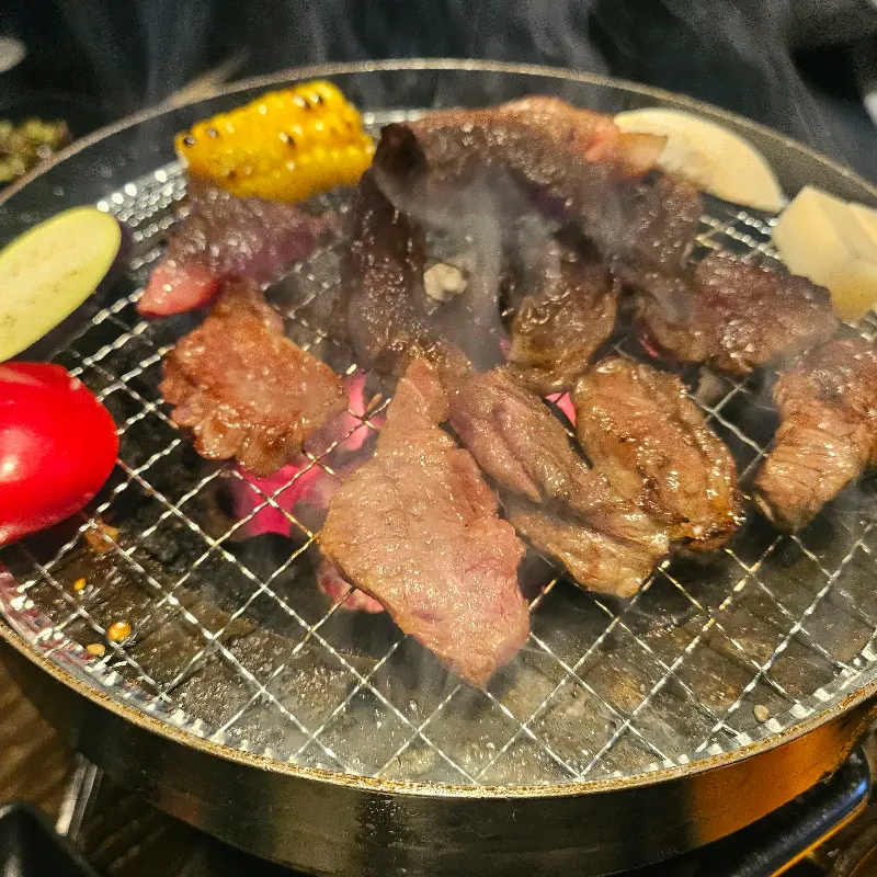 불판 위에서 맛있게 익어가는 고기와 야채