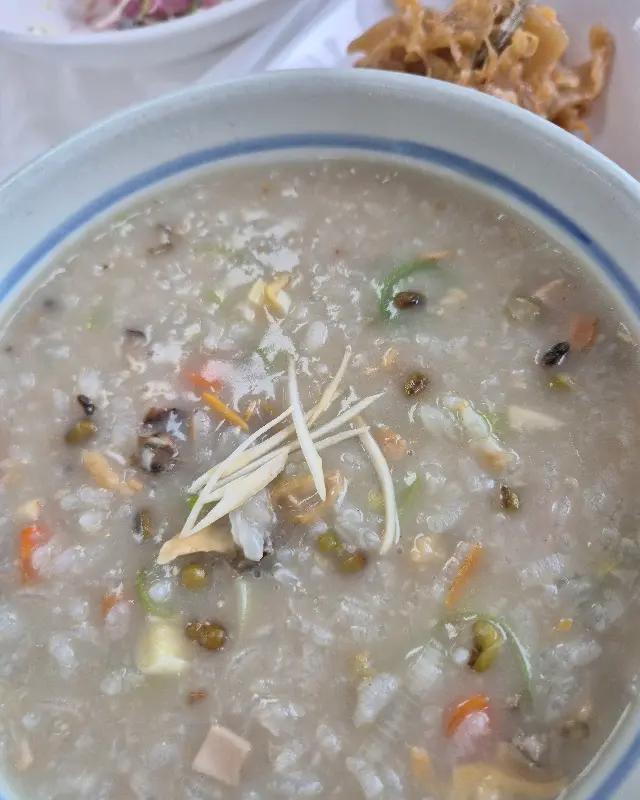 인삼 바지락죽의 클로즈업 사진, 바지락과 녹두 등 다양한 재료들이 보인다.