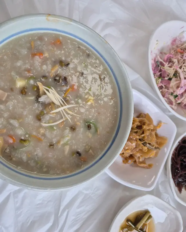 바지락죽과 밑반찬이 함께 놓여 있는 모습.