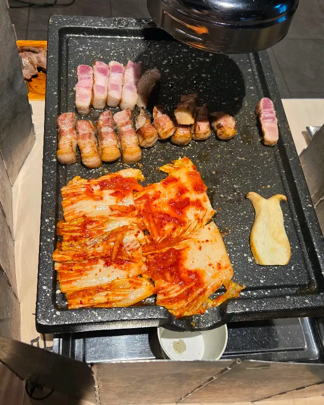 불판 위에서 익어가는 삼겹살과 김치