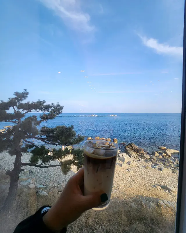 창밖의 바다를 배경으로 놓인 라떼