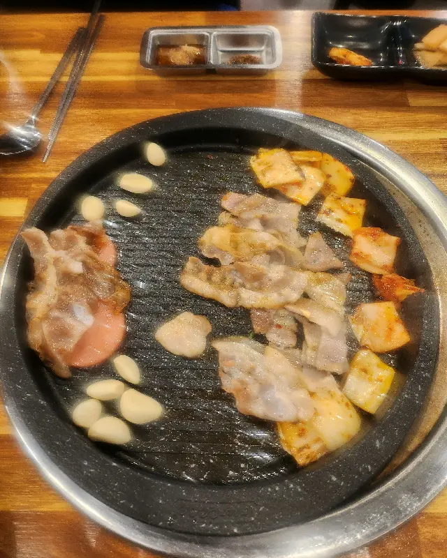 불판 위에서 맛있게 익어가는 냉삼과 김치