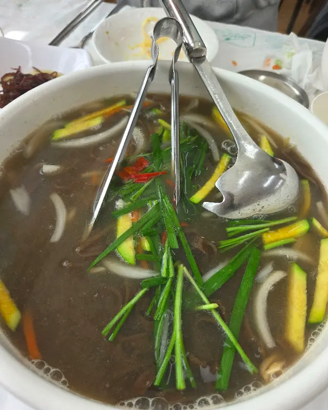 바지락 칼국수의 모습. 쑥갓과 애호박 등 다양한 채소가 면 위에 올려져 있다.