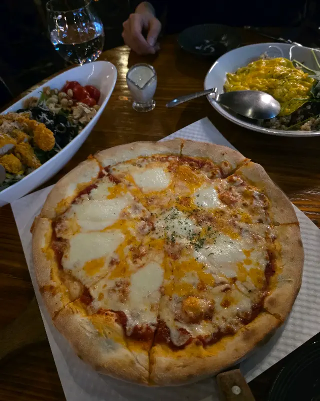 테이블 위에 놓인 피자, 샐러드, 오므라이스의 모습