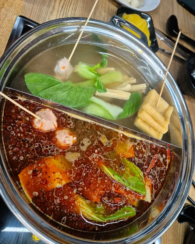 홍탕과 백탕으로 나뉜 훠궈 냄비 안에서 재료들이 끓고 있는 모습