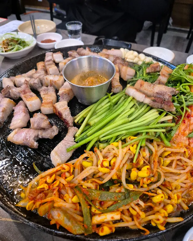 솥뚜껑에 구워진 삼겹살과 야채들