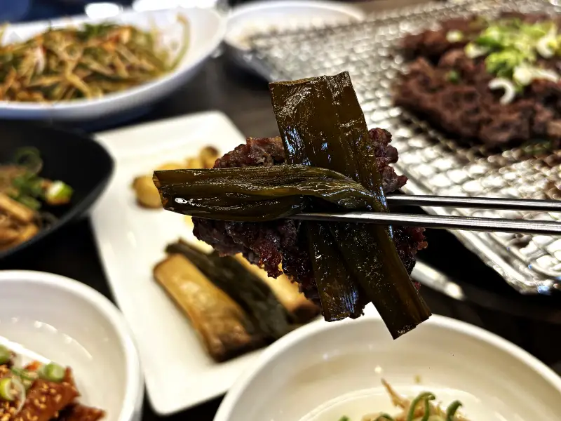 불고기를 장아찌와 함께 젓가락으로 들어 올린 모습