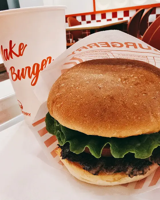 한 손에 든 햄버거와 음료수 컵