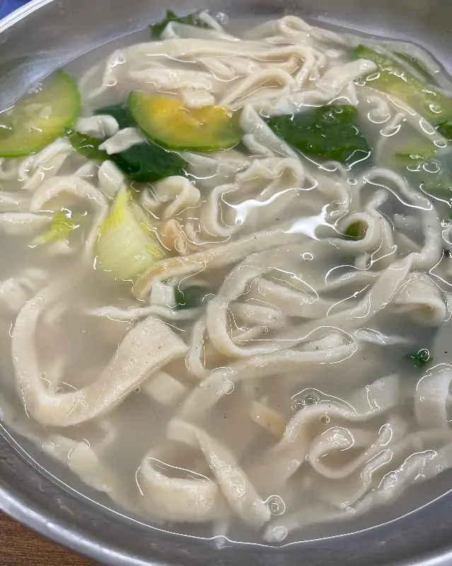 맑은 국물에 담긴 칼국수 면과 채소의 모습
