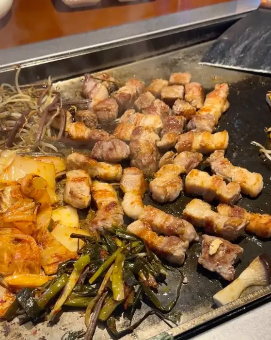 철판 위에서 맛있게 익어가는 삼겹살과 야채들