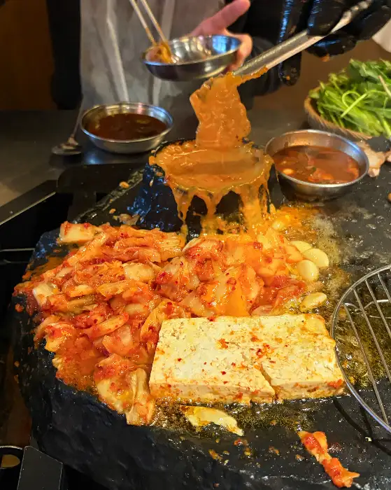 돌판 위 용암 치즈와 고기를 찍는 집게