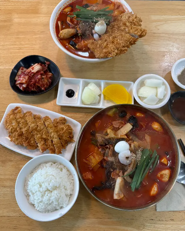 돈까스, 짬뽕, 밥, 김치, 단무지, 짜사이가 한 상 가득 차려진 모습