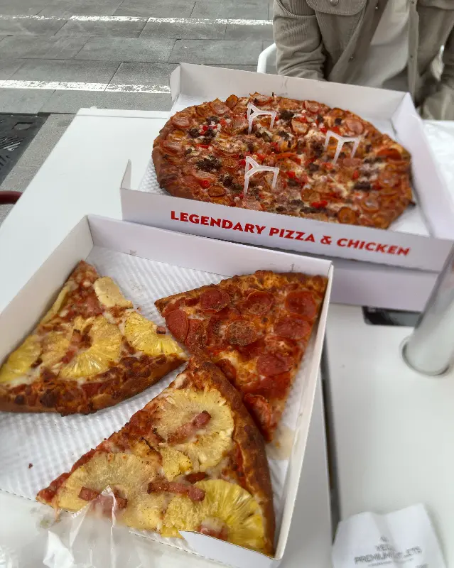 포장 박스에 담긴 하와이안 피자와 페퍼로니 피자 조각