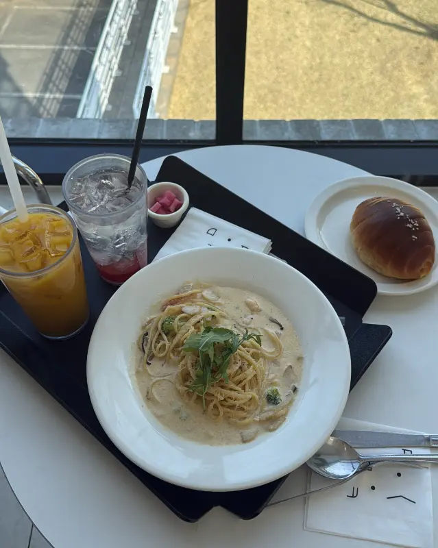 크림 파스타와 음료, 빵이 함께 놓인 쟁반