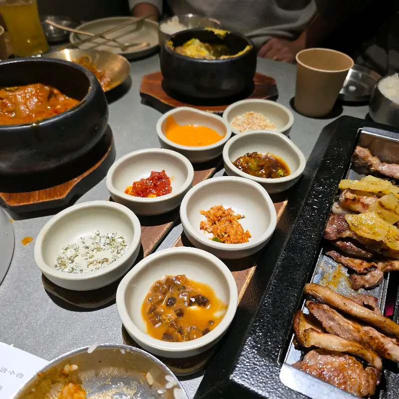 다양한 종류의 밑반찬과 고추장 찌개가 함께 놓인 테이블