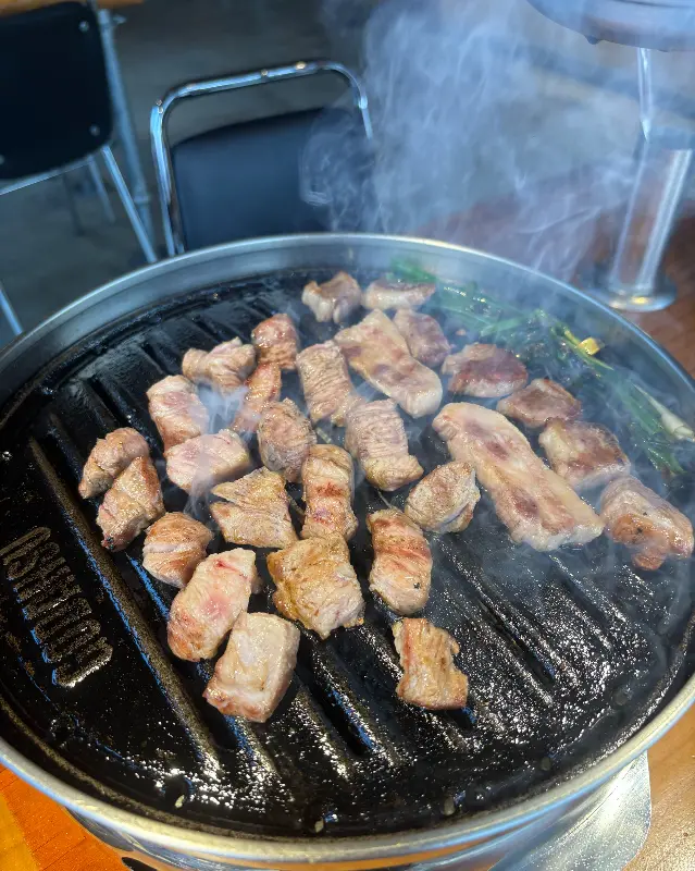 불판 위에 가지런히 놓여있는 삼겹살 조각들.