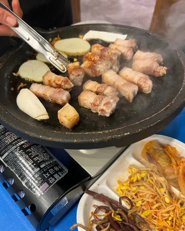 불판 위에서 맛있게 구워지는 오겹살과 감자, 버섯