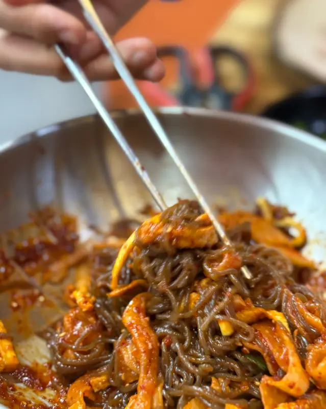 젓가락으로 비빔 막국수를 들어올리는 모습