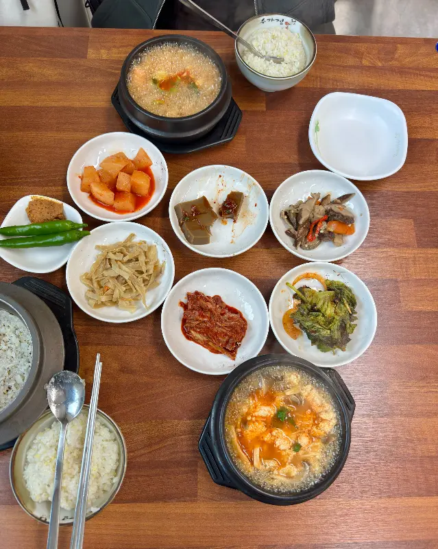 순두부찌개와 갓 지은 돌솥밥, 그리고 다양한 밑반찬이 한 상 가득 차려진 모습