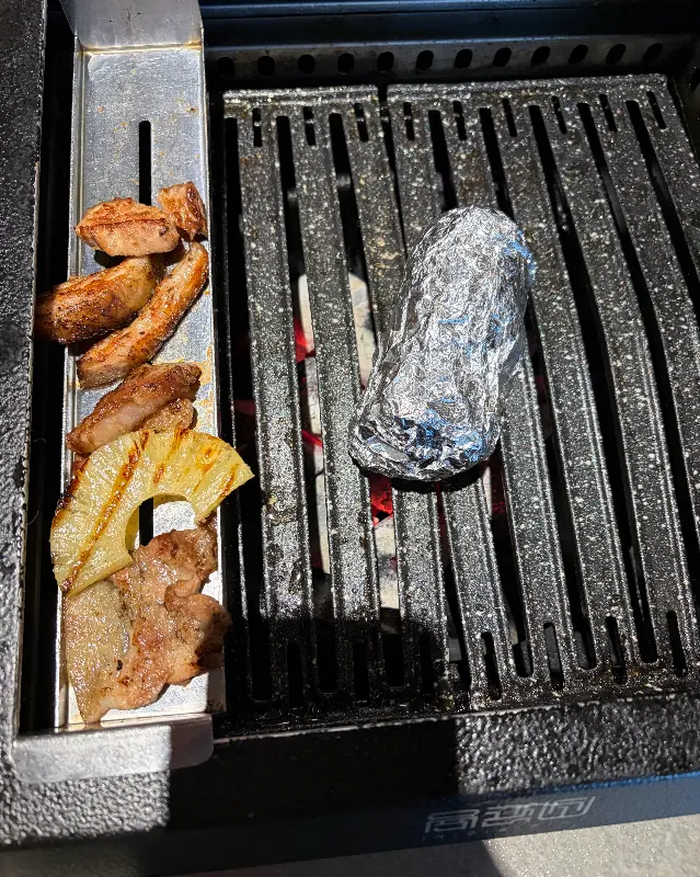 숯불 위에서 맛있게 구워지는 파인애플과 고기 조각