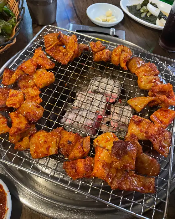 숯불 위에서 막창이 익어가며 맛있는 냄새를 풍기고 있다. 윤기 나는 막창이 군침을 자극한다.