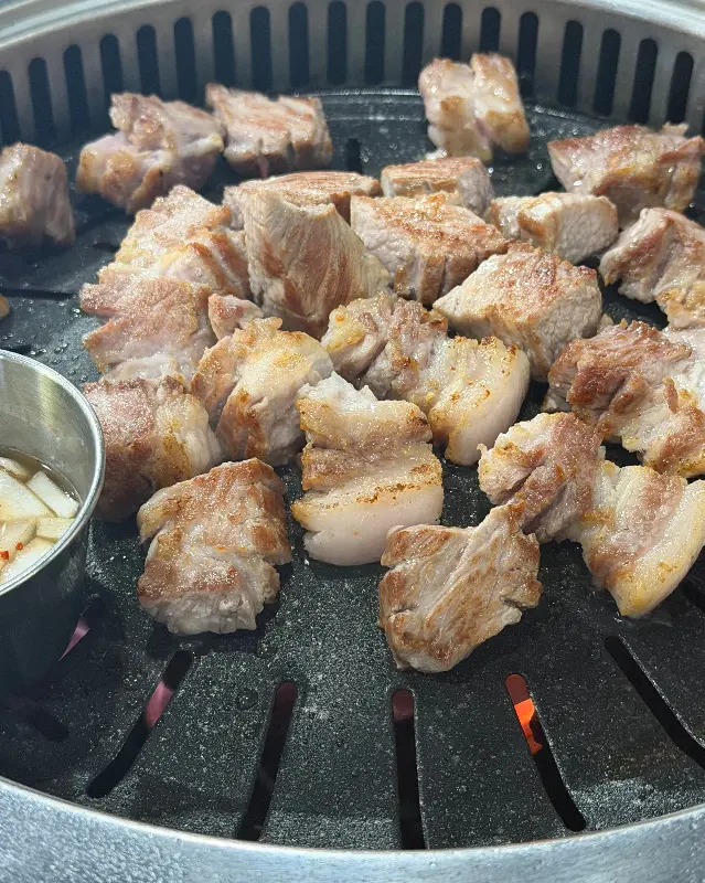 잘 구워진 삼겹살 조각들이 불판 위에 놓여있는 모습