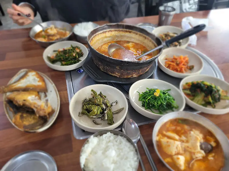 보글보글 끓는 찌개와 다양한 반찬들이 식탁을 가득 채우고 있다.