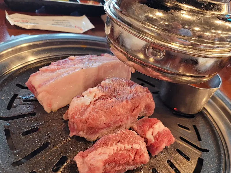 두툼한 생삼겹살과 꽃목살이 숯불 위에서 익어가는 모습