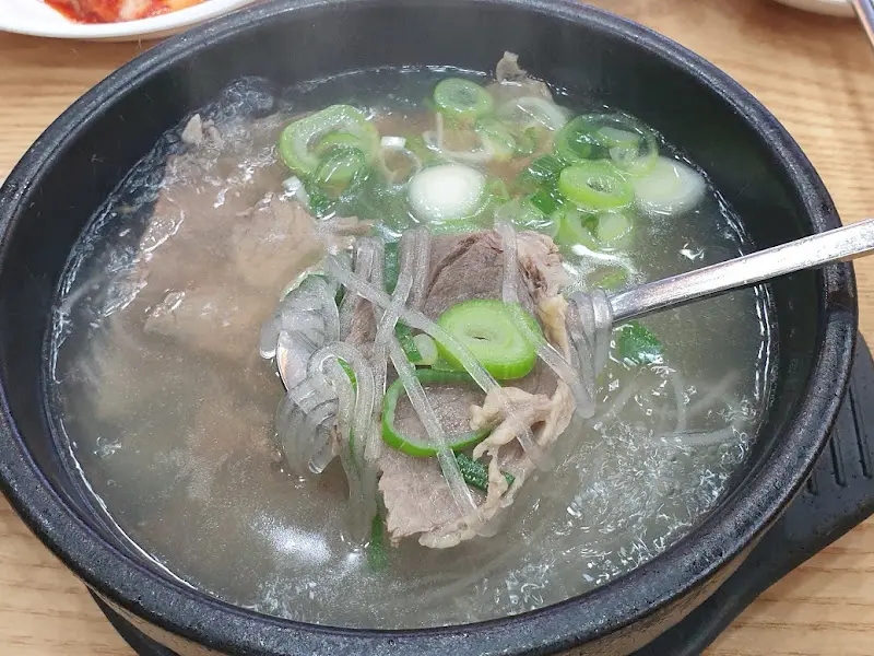 숟가락으로 들어올린 곰탕 속 고기와 면