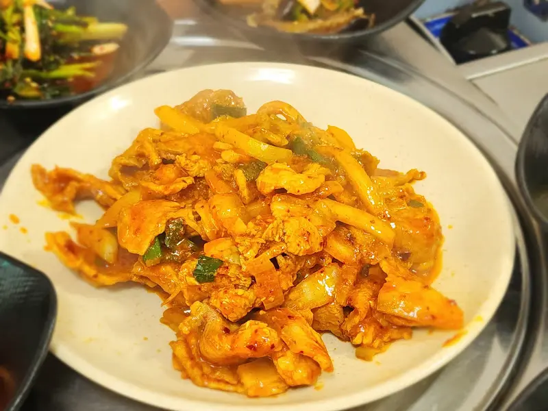 매콤달콤한 제육볶음이 흰 밥 위에 얹어 먹기 좋게 담겨 있다.