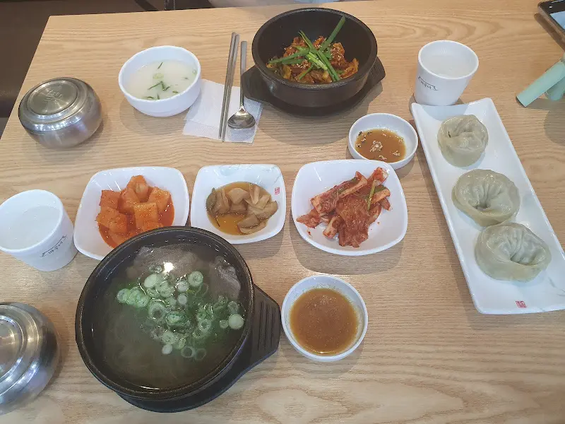 테이블 위에 놓인 다양한 밑반찬과 곰탕, 만두