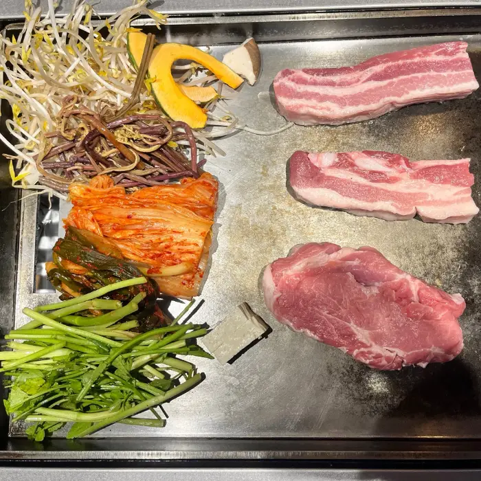 철판 위에 올라갈 삼겹살과 야채들