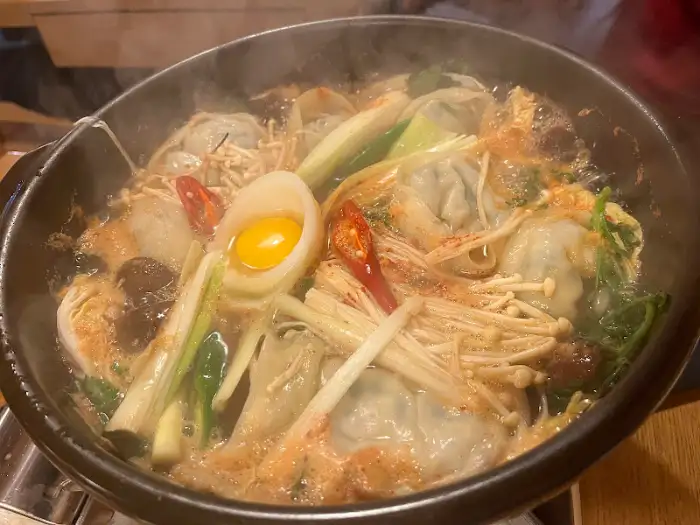 김이 모락모락 나는 만두전골, 다양한 채소와 만두가 푸짐하게 들어있다.
