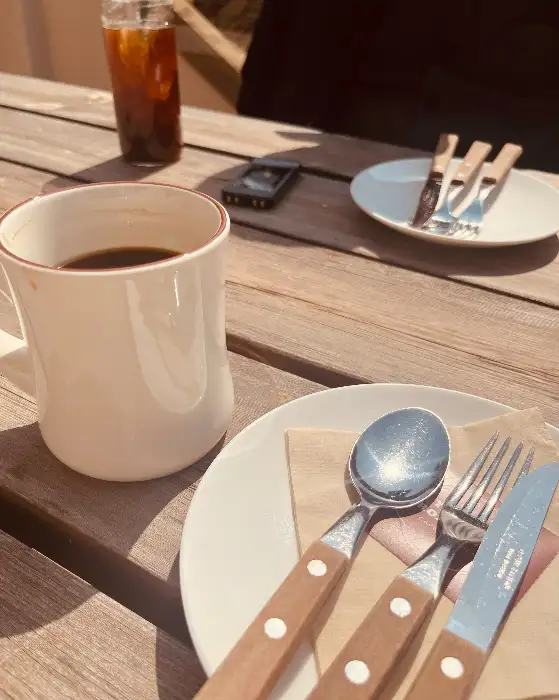 따뜻한 햇살 아래 놓인 커피잔과 식기류