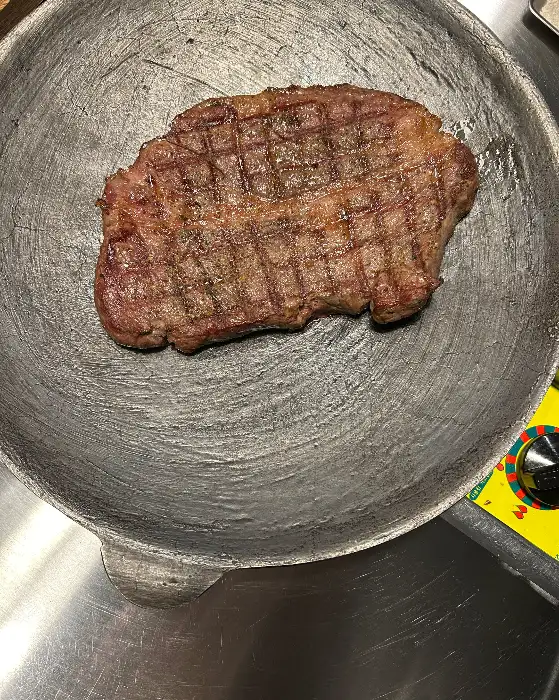 두툼한 고기가 불판 위에 올려져 있습니다.