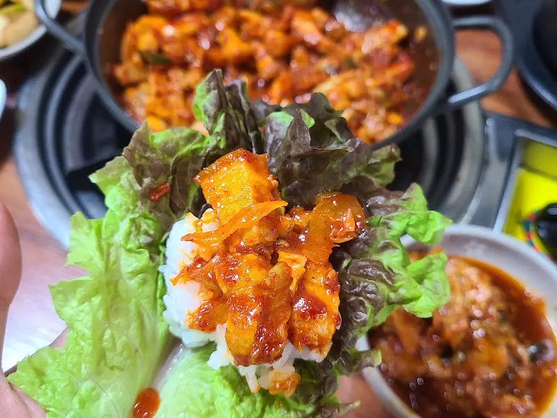 싱싱한 상추에 밥과 삼겹살, 양념을 올려 쌈을 싸는 모습