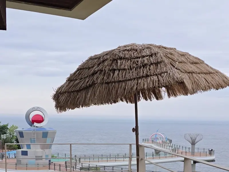 파라솔 아래 앉아 푸른 바다를 감상하며 여유를 즐기는 사람들