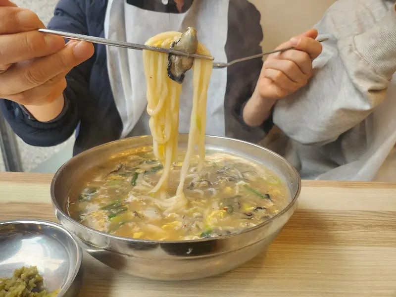 젓가락으로 굴칼국수를 들어올리는 모습