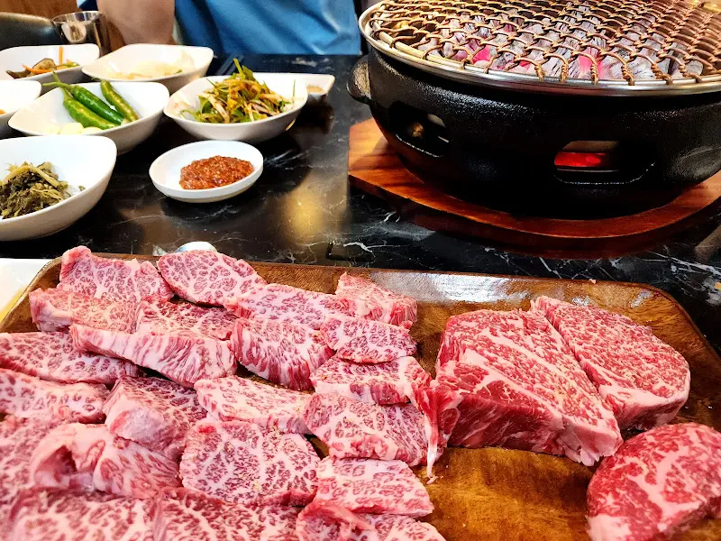 숯불 위에서 익어가는 한우 갈비와 푸짐한 밑반찬