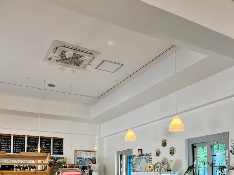 천장이 높고 흰색으로 마감된 식당 내부. 노란색 갓을 씌운 조명이 은은하게 공간을 비추고 있다.