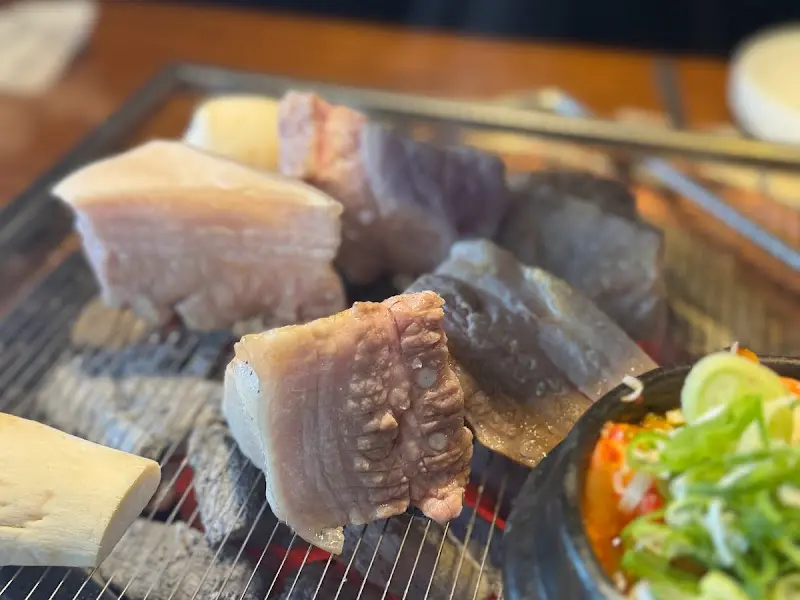 숯불 위에서 익어가는 암퇘지 소금구이와 김치찌개