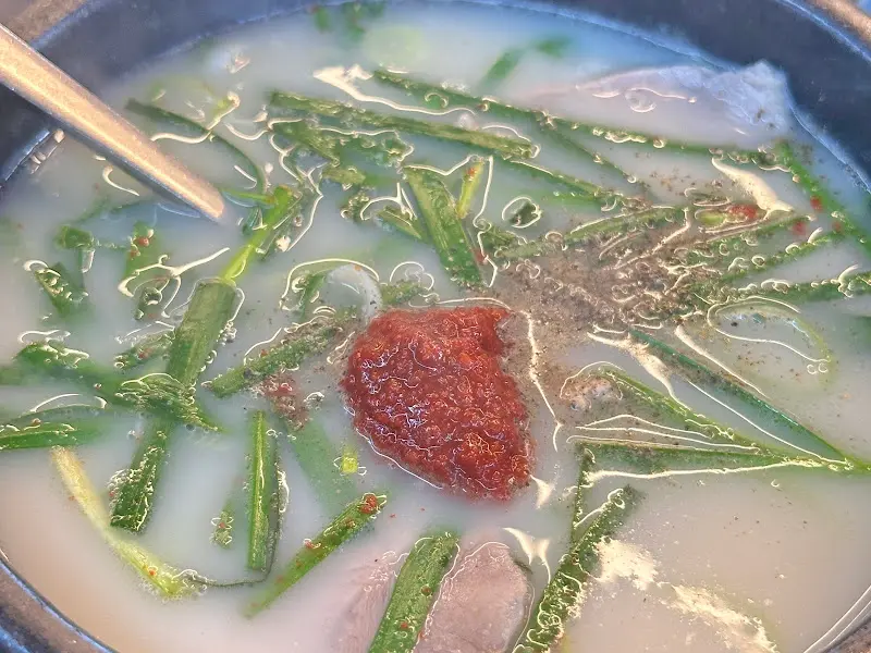 싱싱한 부추와 다진 양념이 올라간 돼지국밥