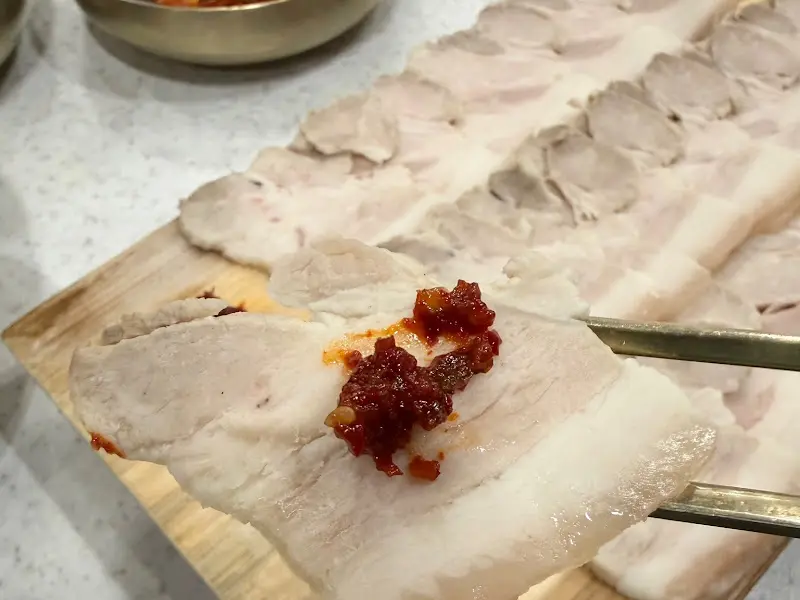 냉수육에 빨간 양념을 곁들여 먹는 모습