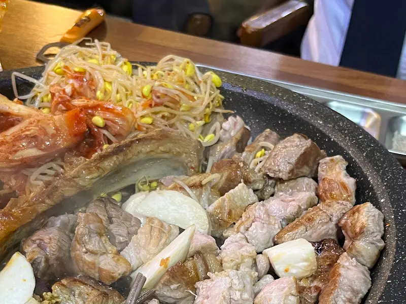 불판 위에 올려진 돼지고기, 김치, 콩나물