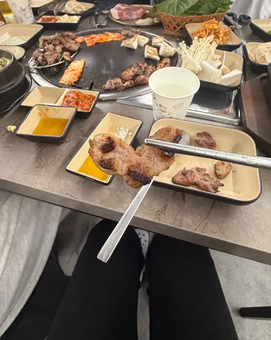 집게로 불판 위 고기를 집어 올리고 있는 모습