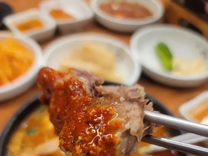 젓가락으로 집어 올린 윤기 나는 수육 한 점