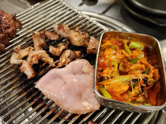 불판 위에서 익어가는 삼겹살과 김치찌개 모습